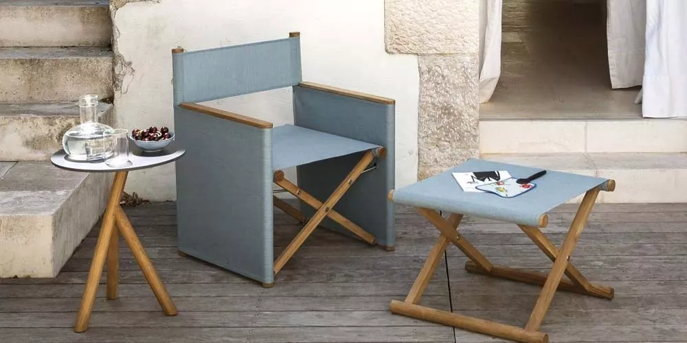 Roda Orson Loungegruppe in Blau auf einer Terrasse mit Holzmöbeln und einem kleinen runden Tisch, entspannte Atmosphäre.