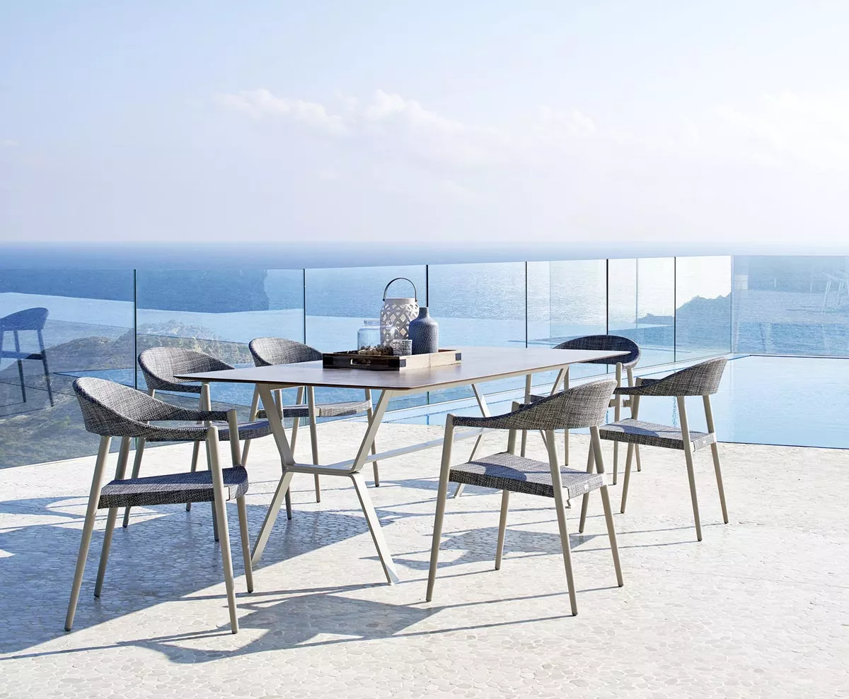 Varaschin Clever Gartenstuhl Essgruppe in Grau auf einer Terrasse mit Meerblick, moderne Outdoor-Möbel in entspannter Atmosphäre.