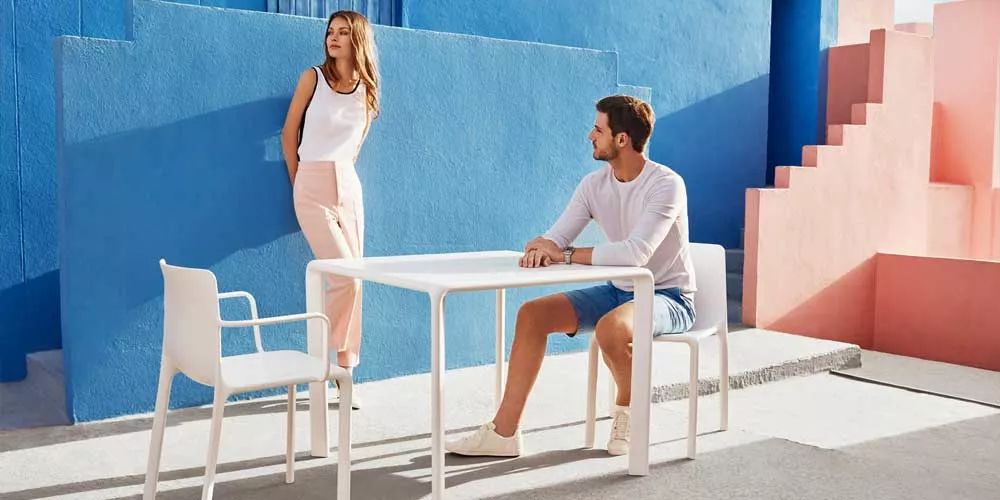 Vondom Kes Essgruppe in Weiß, bestehend aus Tisch und Stühlen, auf modernem, farbenfrohem Hintergrund mit blauem und rosa Wanddesign.