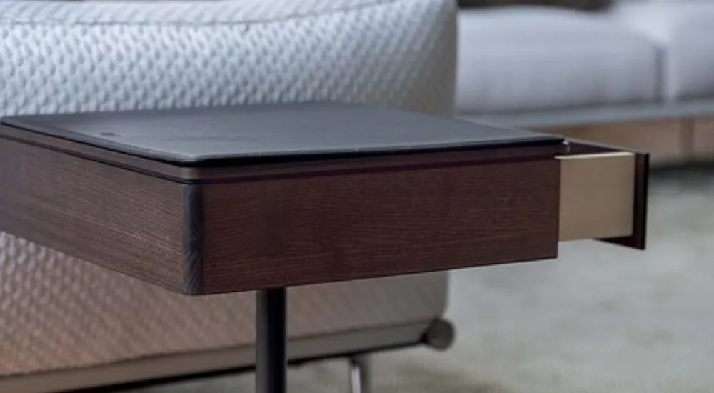 Poltrona Frau BOB Beistelltisch in dunklem Holz mit schwarzer Oberfläche, Detailansicht vor einem strukturierten Stoffhintergrund.