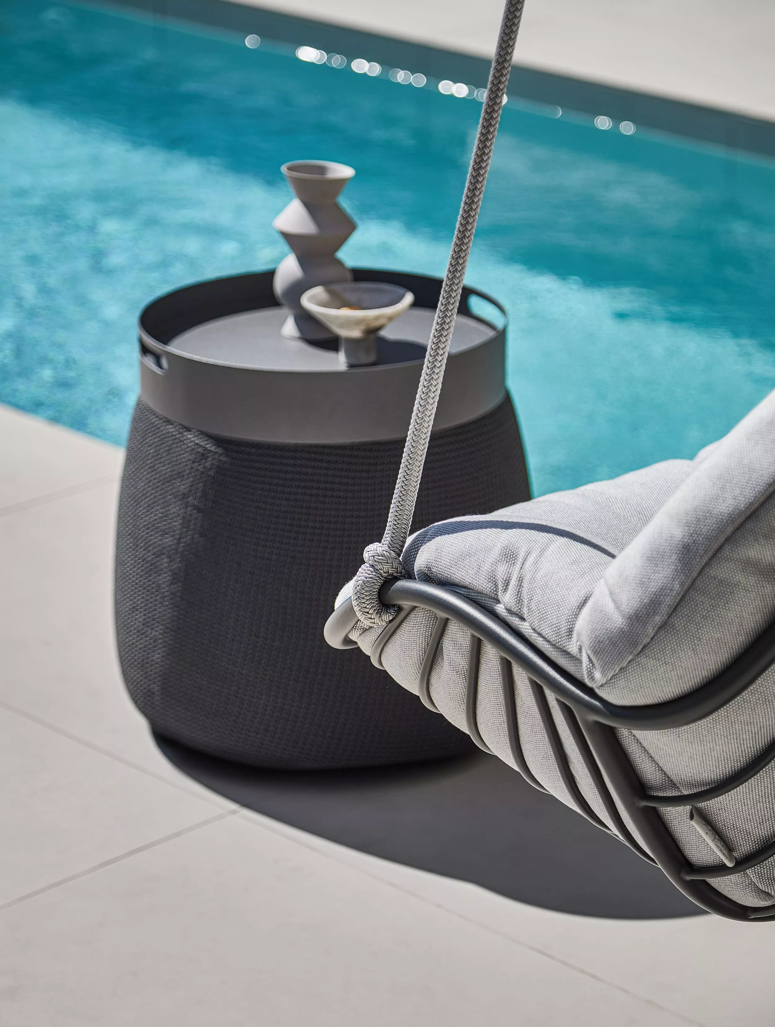 Solpuri Chill-A Hängesessel und Beistelltisch am Pool mit Dekoration in einer entspannten Outdoor-Atmosphäre bei sonnigem Wetter.