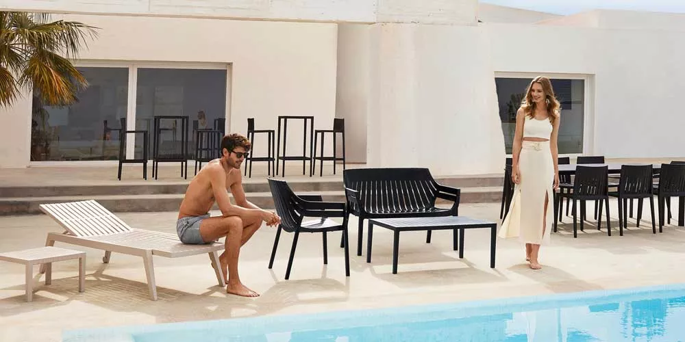 Vondom Spritz Ess- und Loungegruppe in Schwarz und Weiß, Gartenmöbel am Pool, moderne Atmosphäre, mit Palmen im Hintergrund.
