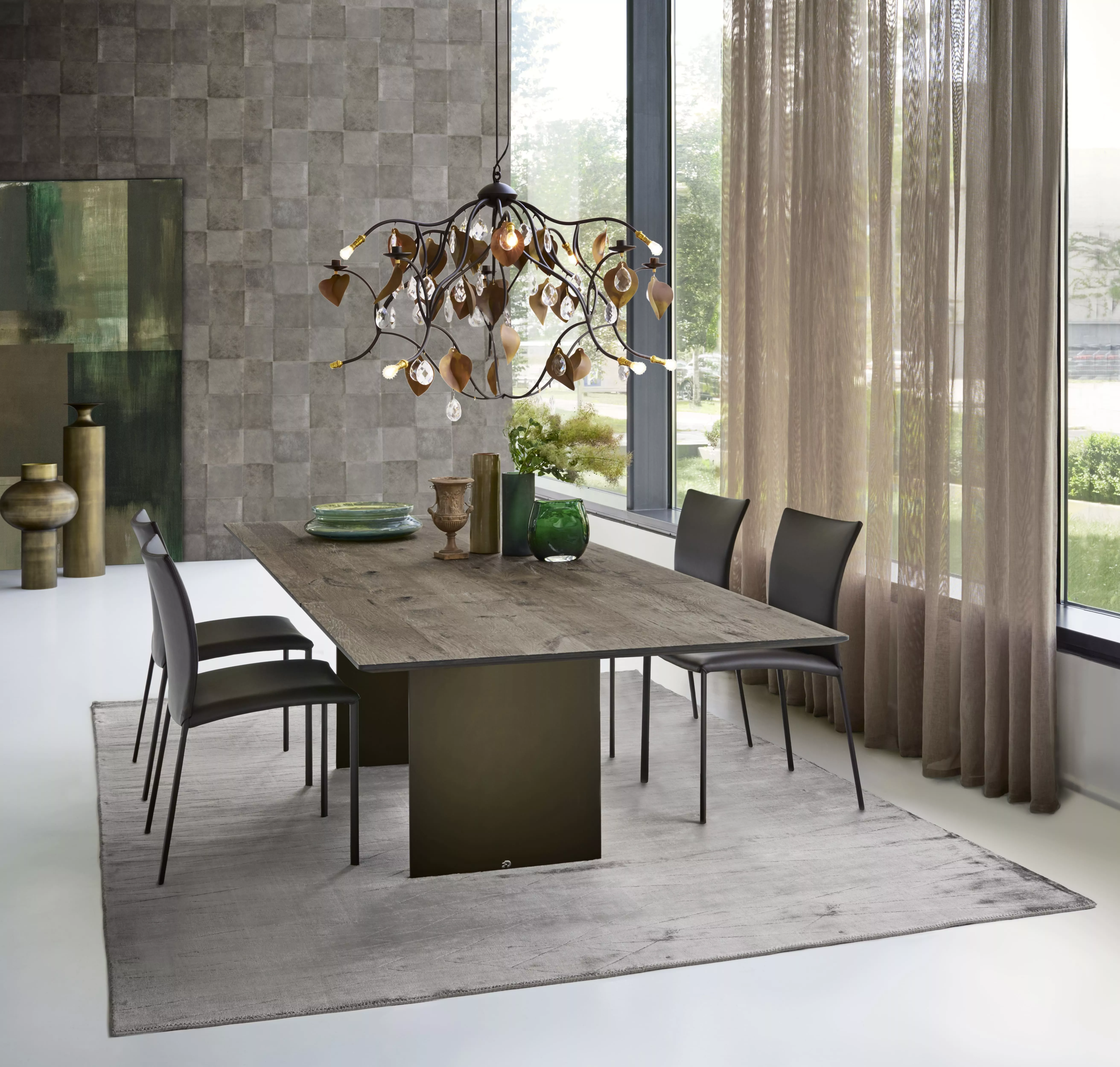 Esszimmer mit DRAENERT Nobile Soft Tisch und Stühlen in modernem Design mit Kronleuchter und Dekoration auf einem Teppich vor großen Fenstern.