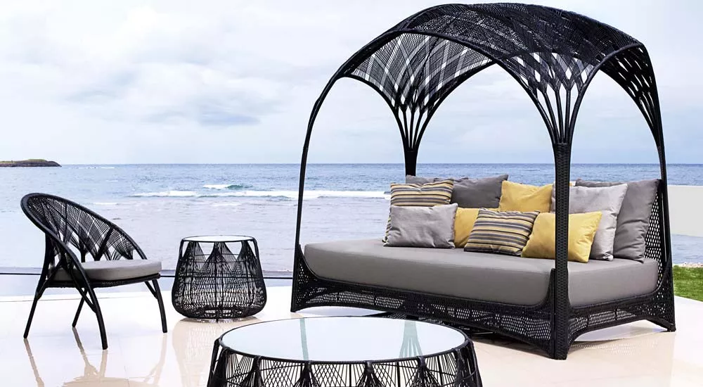 Kenneth Cobonpue Hagia Loungegruppe in Schwarz auf Terrasse mit Meerblick, bestehend aus Sofa, Sessel und Tisch, stimmungsvolle Außenaufnahme.