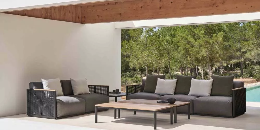Gandia Blasco BOSC Outdoor-Sofa in Anthrazit auf einer Terrasse mit Waldblick und Pool im Hintergrund.