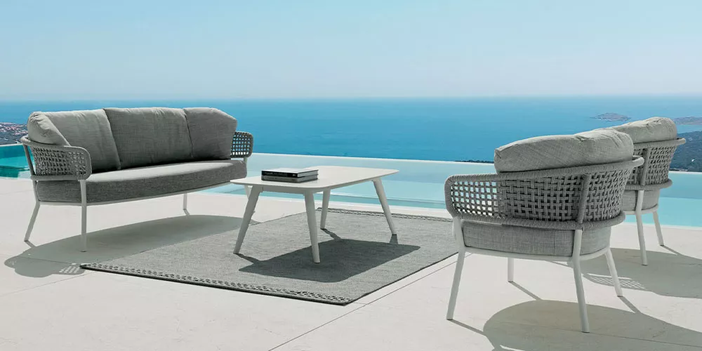 Talenti Kollektion Moon in Grau, bestehend aus Sofa, zwei Sesseln und Tisch, auf Terrasse mit Meerblick.