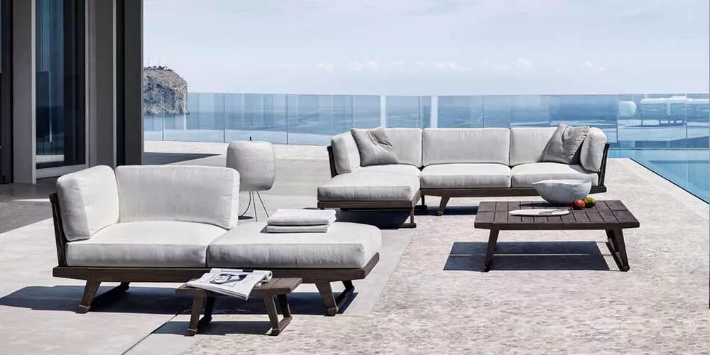 BeB Italia Gio Outdoor Loungegruppe in Weiß auf einer Terrasse mit Meerblick, bestehend aus Loungesofa, Sessel und Couchtisch.