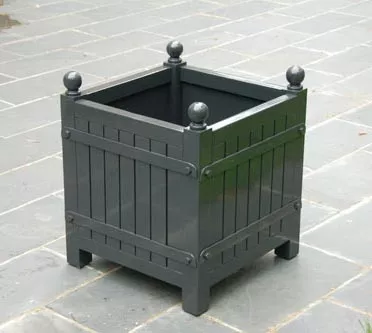 Orangerie Pflanzkübel aus lackiertem Akazienholz auf grauem Steinboden stehend