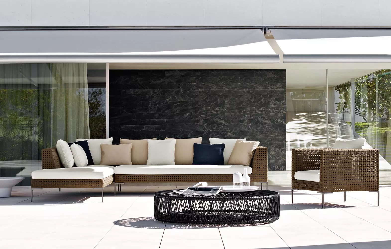 Charles Outdoor Endelement links 160 cm von B&B Italia auf einer Terrasse mit Kissen und einem runden Couchtisch im Freien.