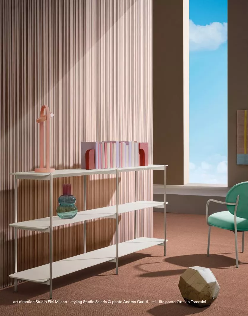Ein weißes Regal von Studio FM Milano steht in einem modernen Raum mit pastellfarbenen Wänden und einem großen Fenster mit Blick auf den Himmel.