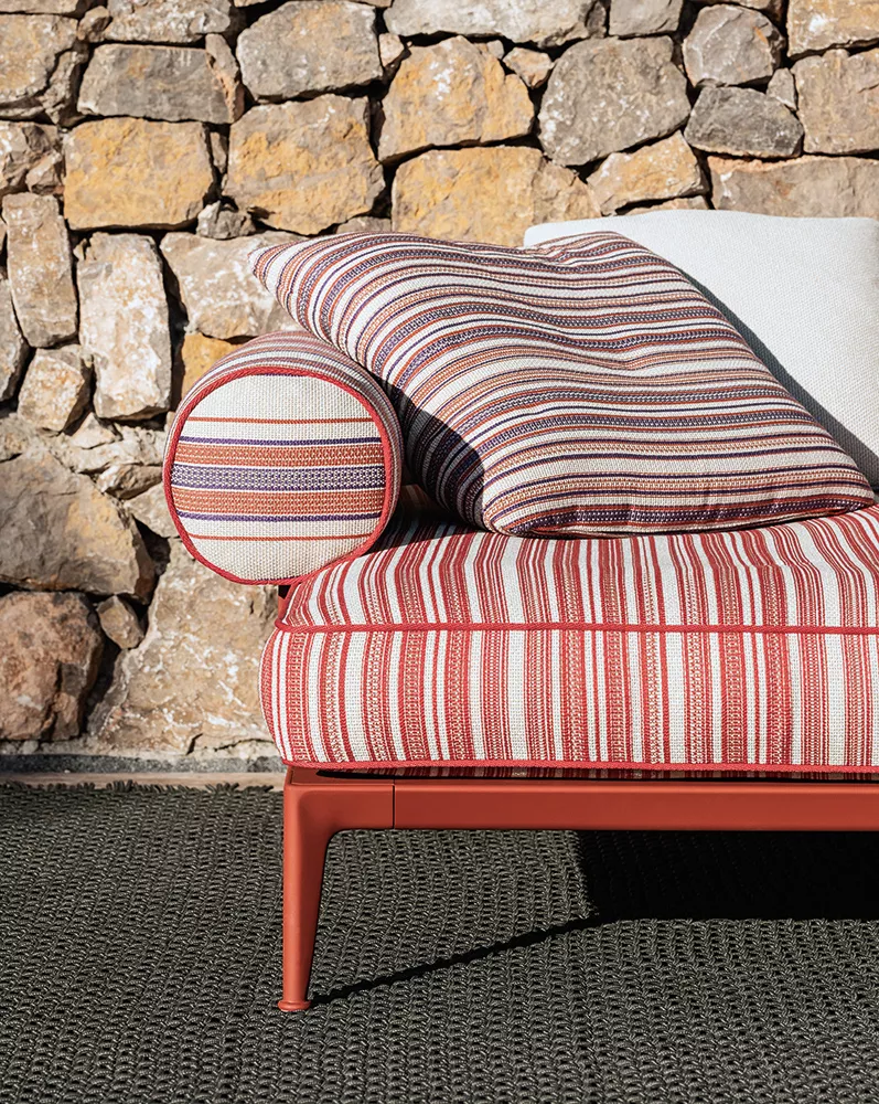 B&B Italia Ribes Outdoor Lounge mit gestreiften Kissen und Polstern vor einer Steinmauer