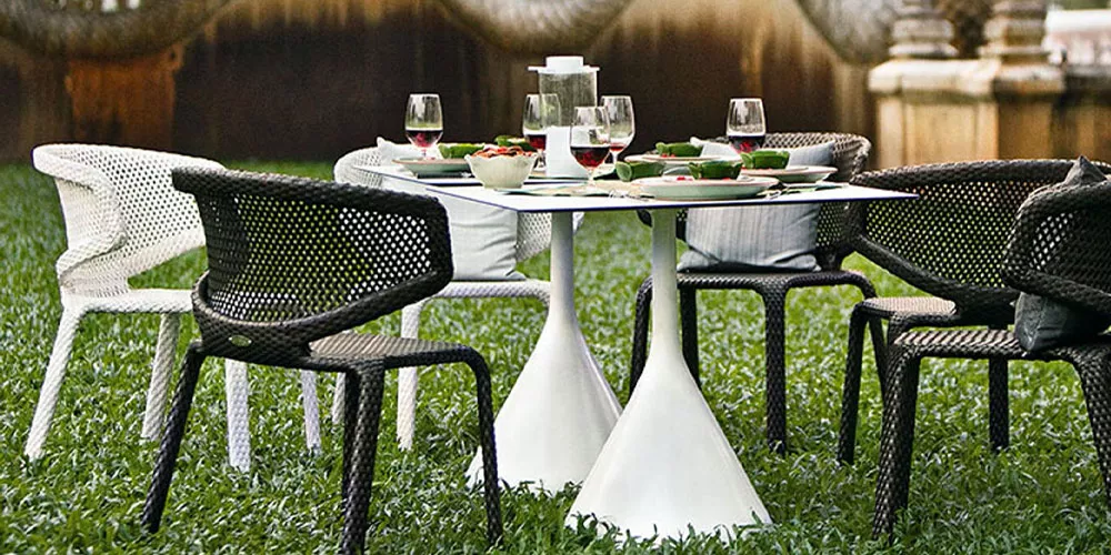 Dedon Kollektion Satellite zeigt einen gedeckten Tisch mit vier Stühlen im Garten ideal für ein gemütliches Essen im Freien