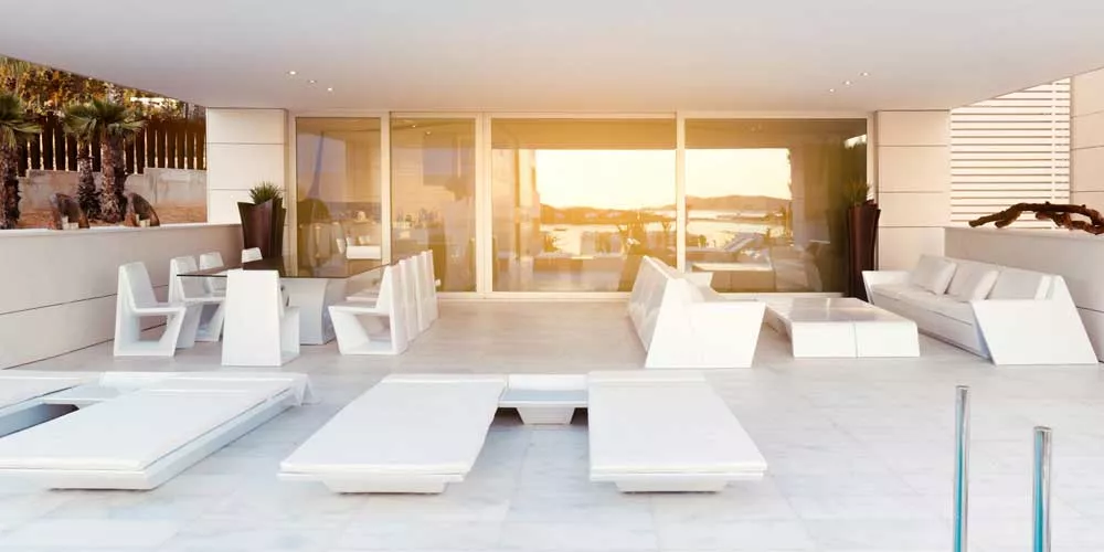 Vondom Rest Essgruppe in Weiß auf einer modernen Terrasse mit Blick auf den Sonnenuntergang über dem Wasser.