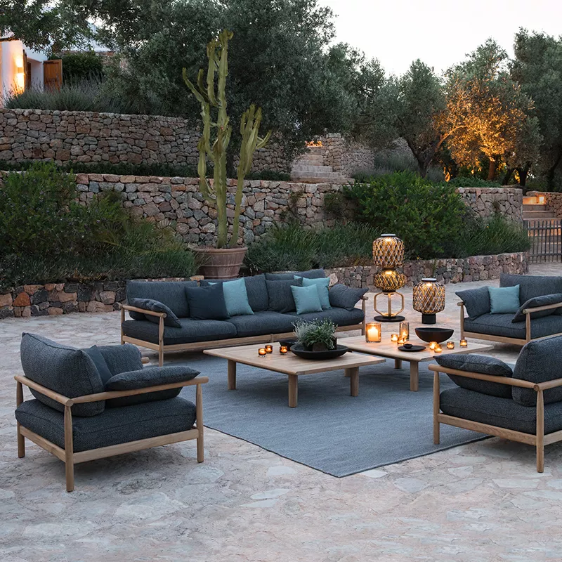 Dedon Orbit Deko Kissen 62 x 25 cm auf einer stilvollen Terrasse mit modernen Outdoor-Möbeln und stimmungsvoller Beleuchtung im Hintergrund.