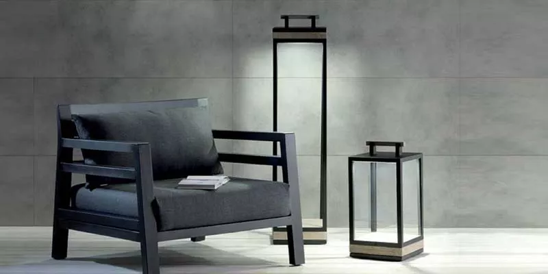 Ethimo Carre Outdoor Gartenleuchten in Schwarz, stimmungsvolle Beleuchtung neben einem modernen Sessel vor einer grauen Wand.