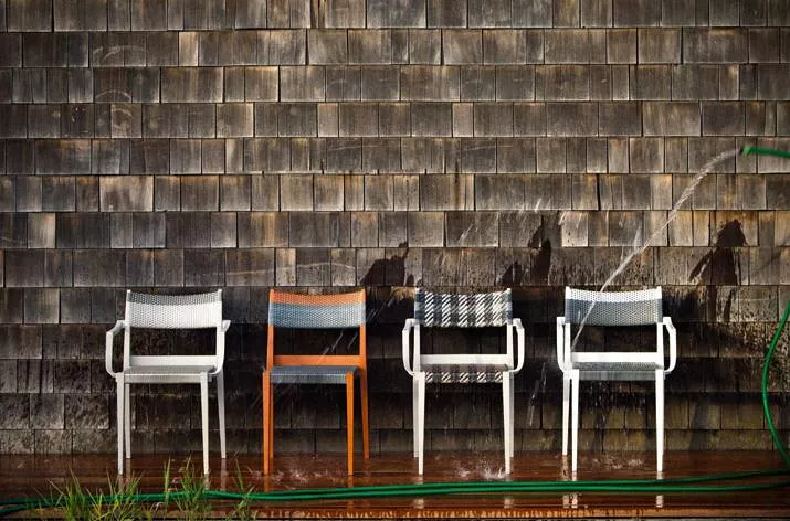 Vier Dedon Play Essstühle in verschiedenen Farben werden im Freien mit einem Wasserschlauch abgespritzt Moodbild