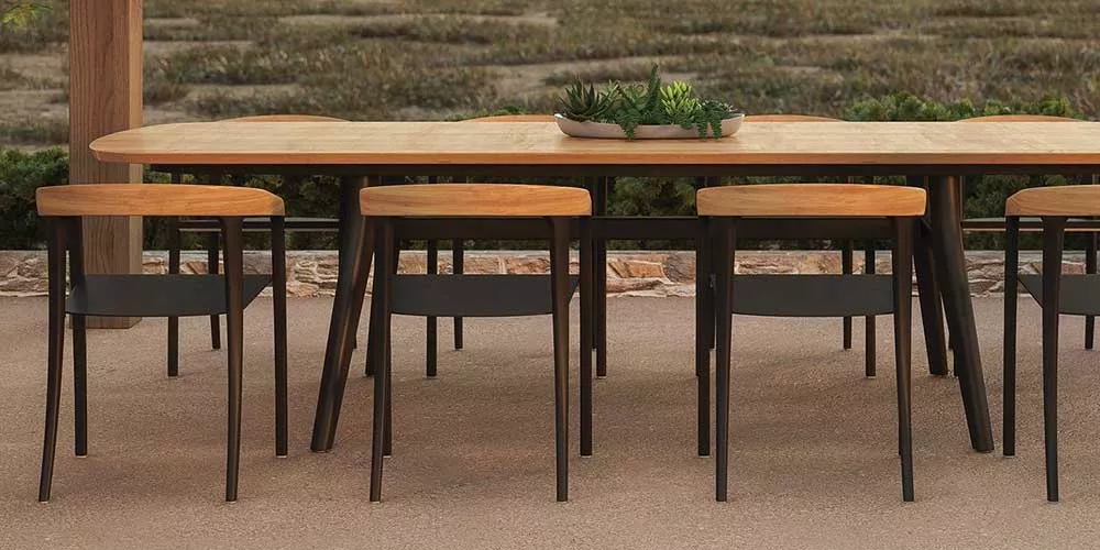 Royal Botania Jive Essgruppe in Holzoptik auf Terrasse mit Naturhintergrund, bestehend aus Tisch und sechs Stühlen, stimmungsvolles Ambiente.