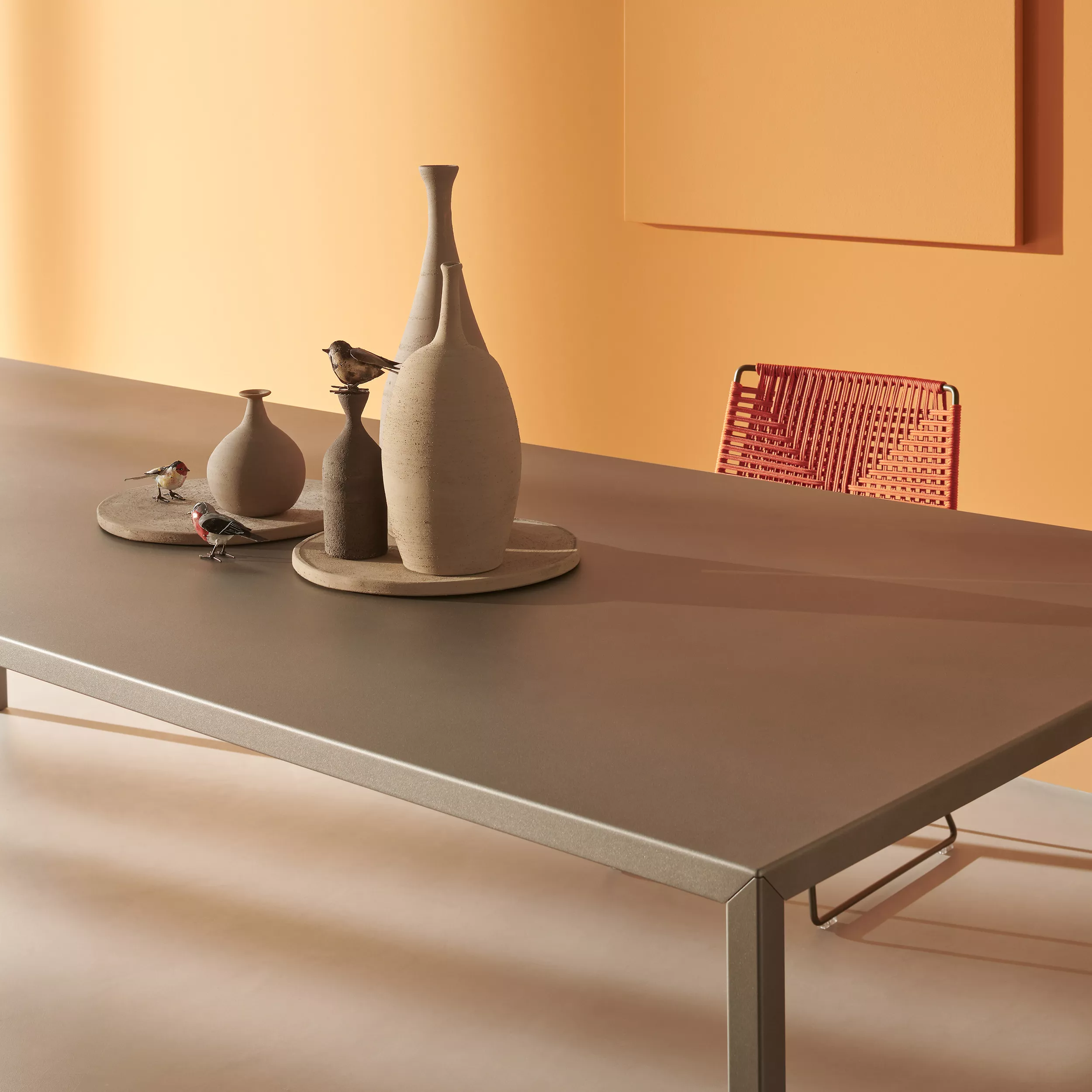 MDF Italia Tense Tisch in einem modernen Raum mit Vasen und dekorativen Vögeln auf dem Tisch und einem roten Stuhl im Hintergrund