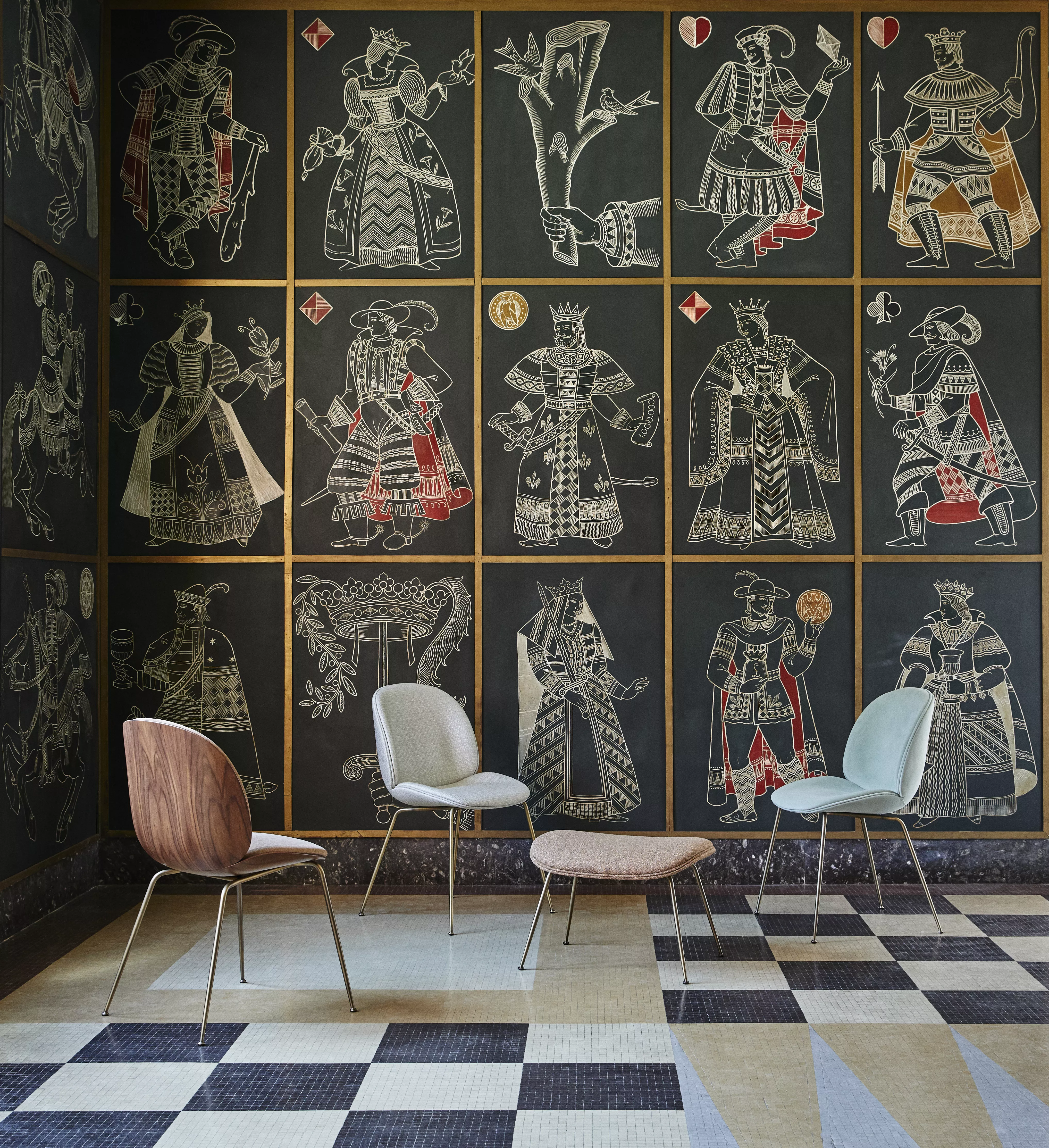 Drei Gubi Stühle und ein Couchtisch stehen in einem Raum mit kunstvoll bemalten Wänden die historische Figuren darstellen
