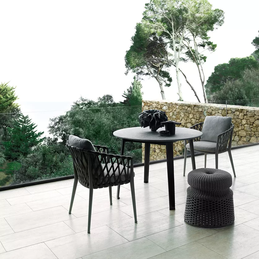 B&B Italia Ginepro Tisch 105cm mit zwei Stühlen und einem Hocker auf einer Terrasse mit Blick auf Bäume und das Meer