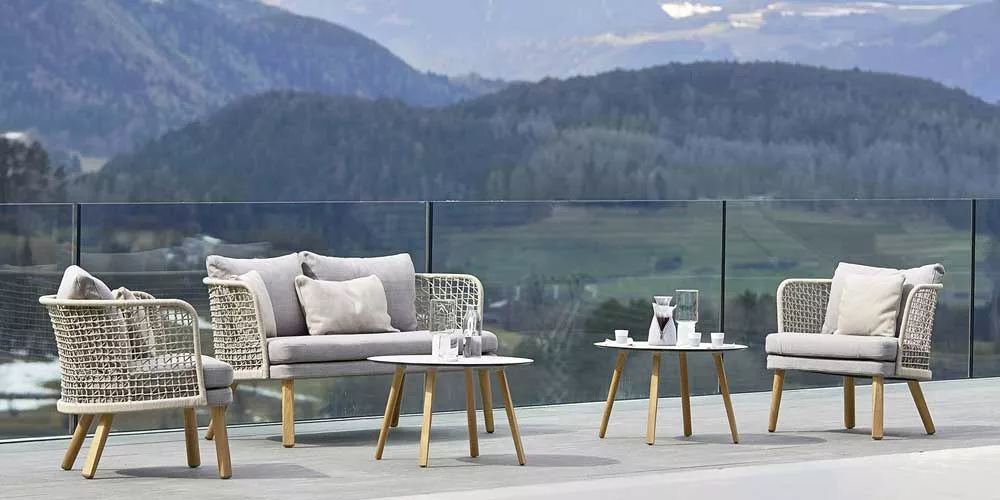 Varaschin Emma Loungegruppe in Beige auf Terrasse mit Bergblick, bestehend aus Sofa, Sesseln und Tisch, ideal für Gartenmöbel-Set.