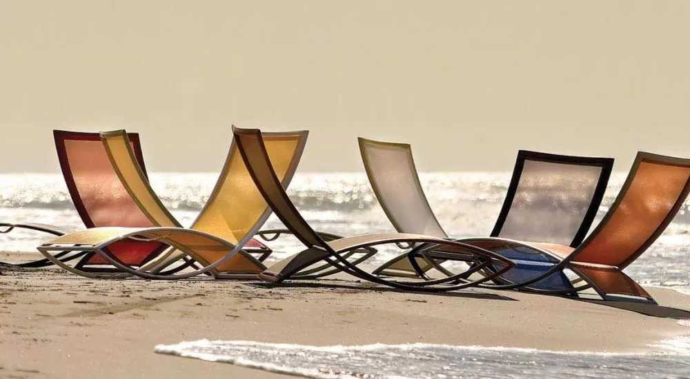 EGO Paris Premiere Loungegruppe in verschiedenen Farben am Strand vor einem ruhigen Meer, stimmungsvolles Bild bei Sonnenuntergang.