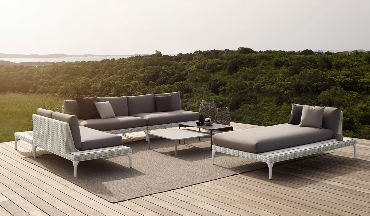 Dedon Loungesofa auf einer Terrasse mit Blick auf eine grüne Landschaft und einem Tisch in der Mitte