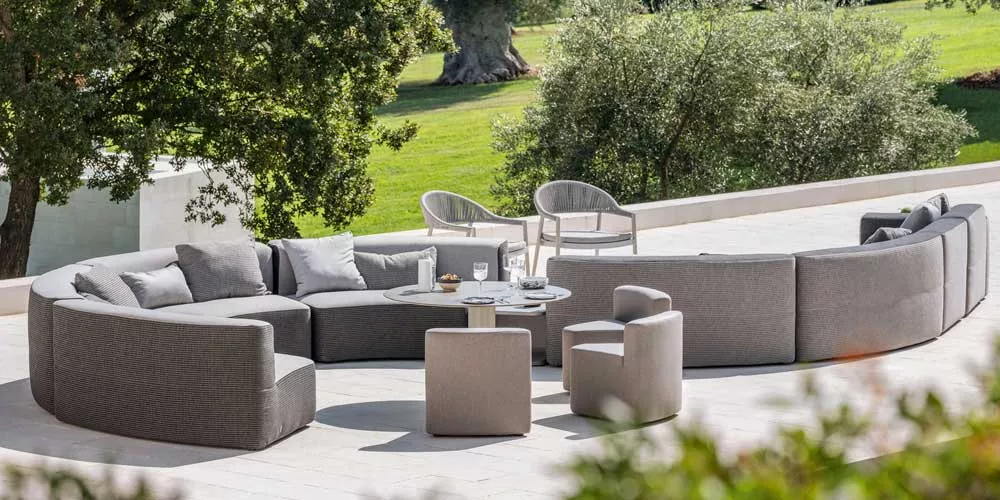 Varaschin Belt Lounge Gartenmöbel in Grau auf einer Terrasse mit Blick auf einen grünen Garten, bestehend aus modularen Sofas und Sesseln.