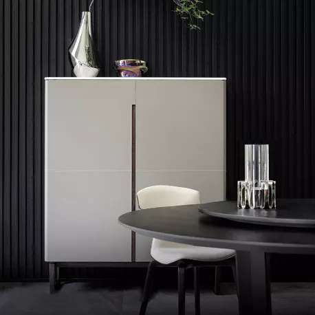 Poltrona Frau Fidelio Cabinet Highboard in Marmoroptik vor schwarzer Wand, mit Dekorationen und modernem Esszimmer im Vordergrund.