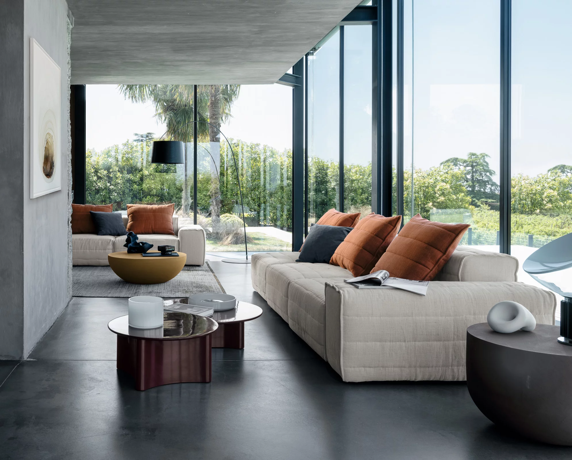 Gervasoni Samet Sofa in einem modernen Wohnzimmer mit großen Fenstern und Blick auf einen Garten mit Palmen und Bäumen