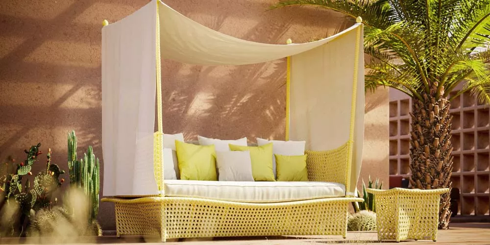 Dedon Daydream Daybed in einer Wüstenoase mit Kissen und Pflanzen im Hintergrund