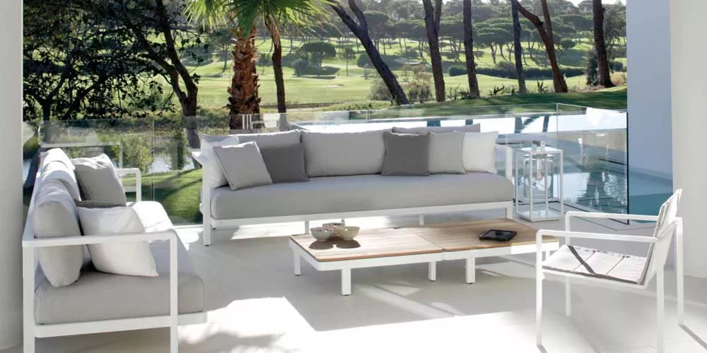 Royal Botania Alura Lounge Gartenmöbel in Weiß auf einer Terrasse mit Blick auf einen grünen Golfplatz bei sonnigem Wetter.