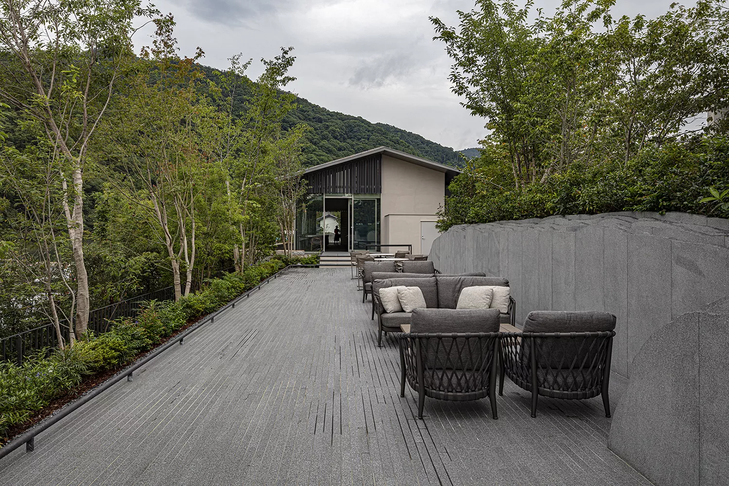 B&B Italia Erica Loungesofa 216 cm auf einer Terrasse mit Blick auf ein modernes Haus und umgeben von Bäumen und Bergen im Hintergrund