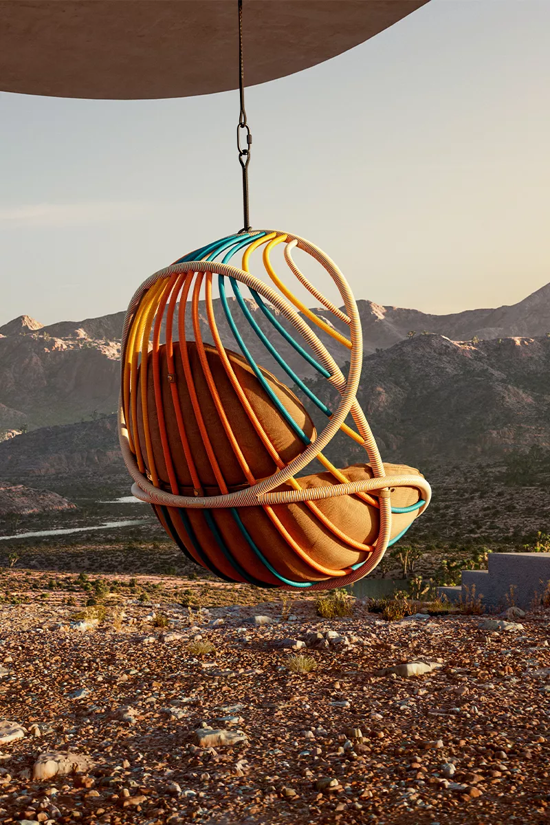 Der Dedon Kida Sessel hängt in einer malerischen Berglandschaft und bietet einen farbenfrohen und gemütlichen Sitzplatz in der Natur.
