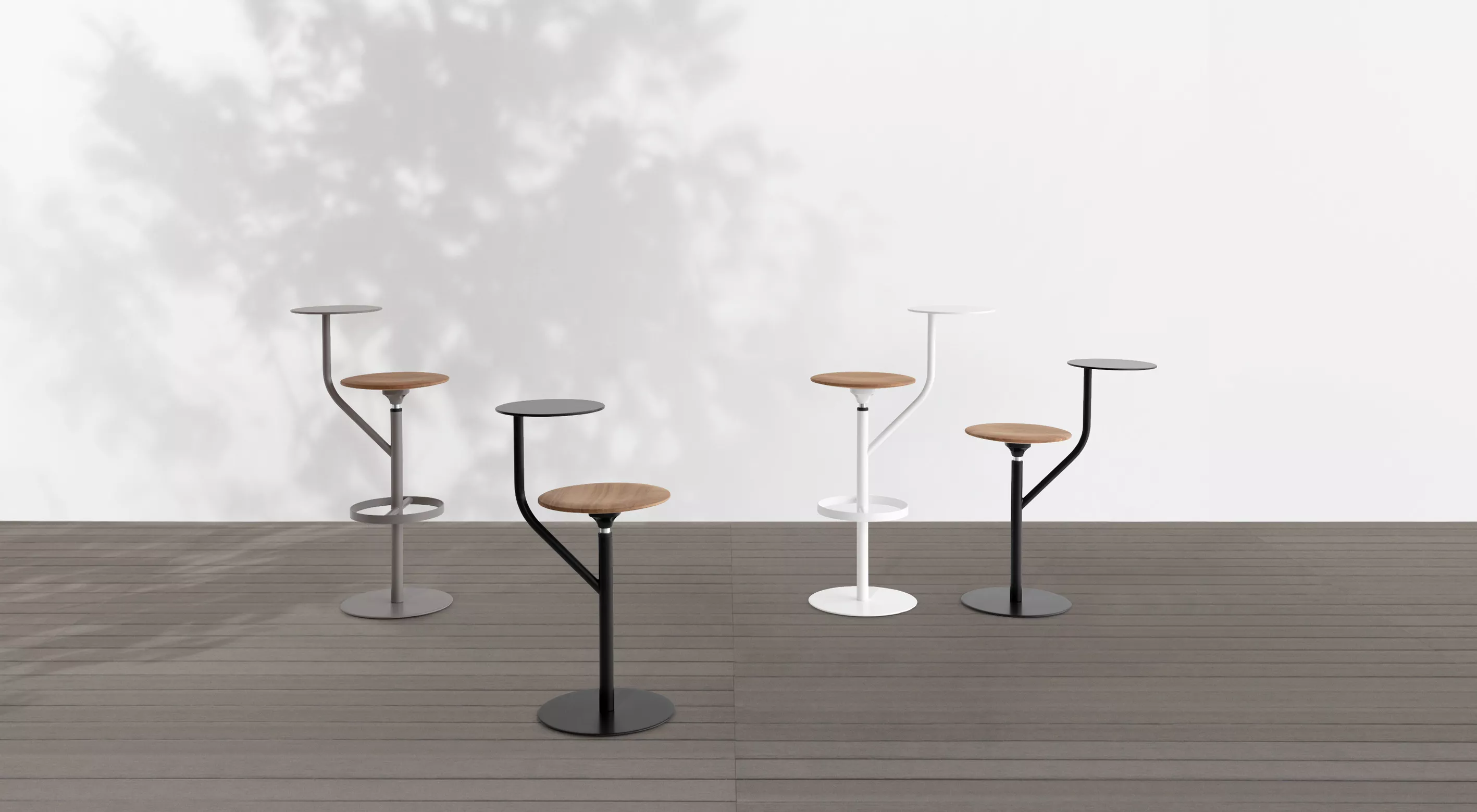 Vier AARON Outdoor-Barhocker von Villa Schmidt in Schwarz, Weiß und Grau auf einer Holzterrasse mit Schatten eines Baumes im Hintergrund.