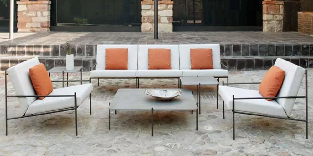 POINT Min Outdoor-Loungegruppe in Weiß und Orange auf einer Stein-Terrasse, bestehend aus Sofa, Sesseln und Tisch, stimmungsvolle Atmosphäre.