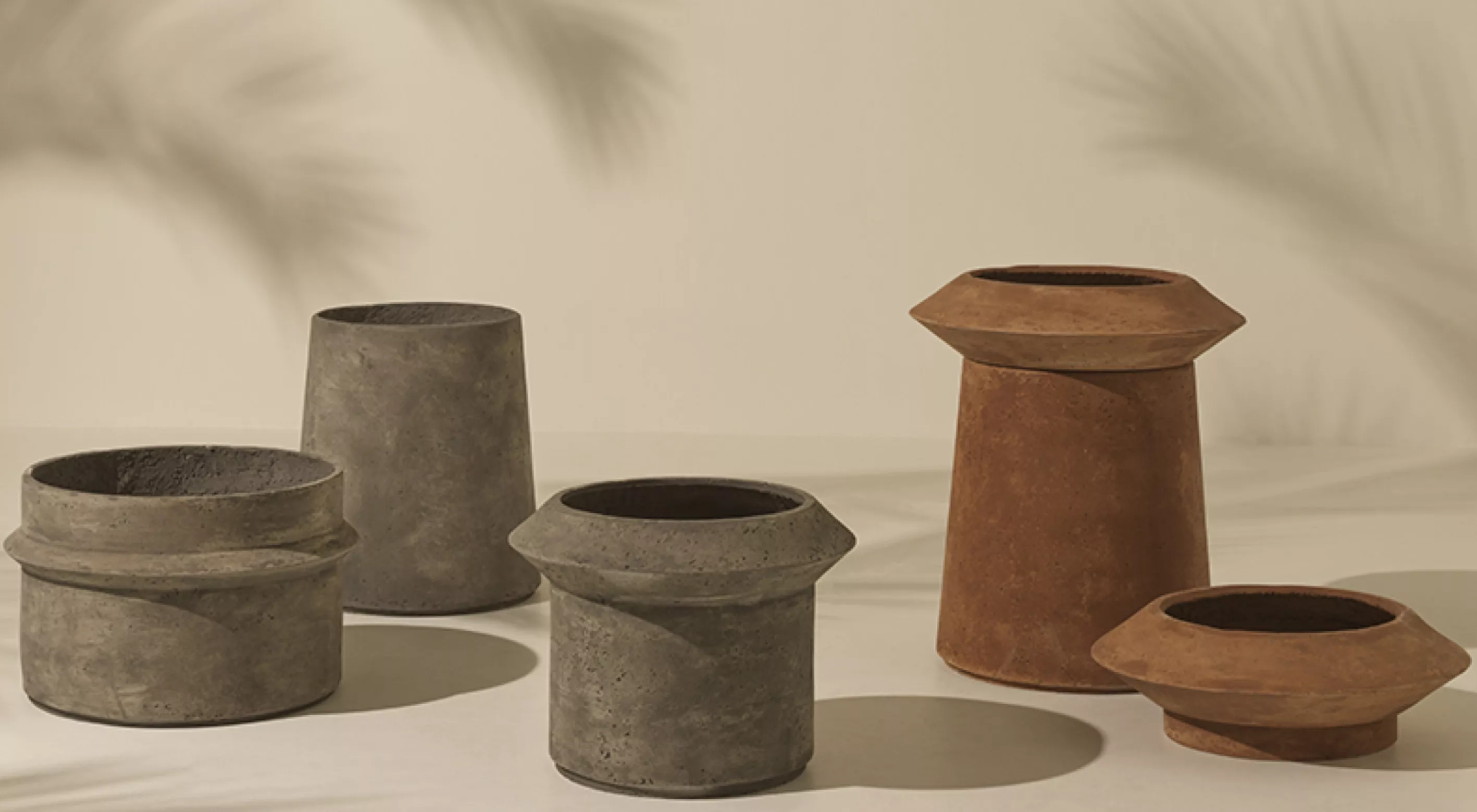 Fünf rustikale Blumentöpfe von Villa Schmidt in verschiedenen Größen und Erdtönen auf einem sandfarbenen Hintergrund mit Schatten.