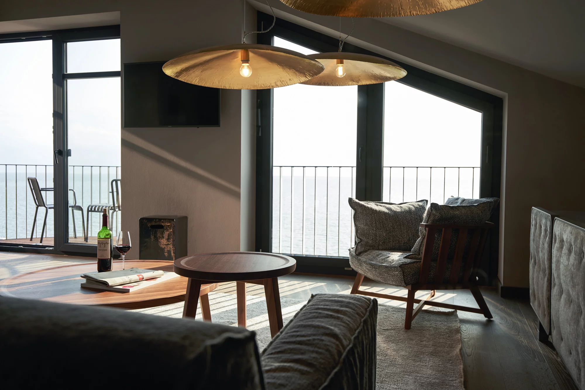 Gemütliches Wohnzimmer mit Gervasoni Möbeln und Blick auf das Meer durch große Fenster im Hintergrund zwei Stühle auf dem Balkon