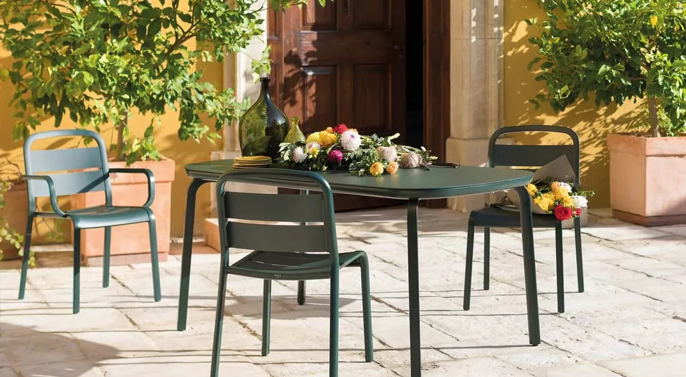 EGO Paris Marumi Essgruppe in Dunkelgrün auf einer sonnigen Terrasse mit Blumenarrangement, mediterrane Stimmung.