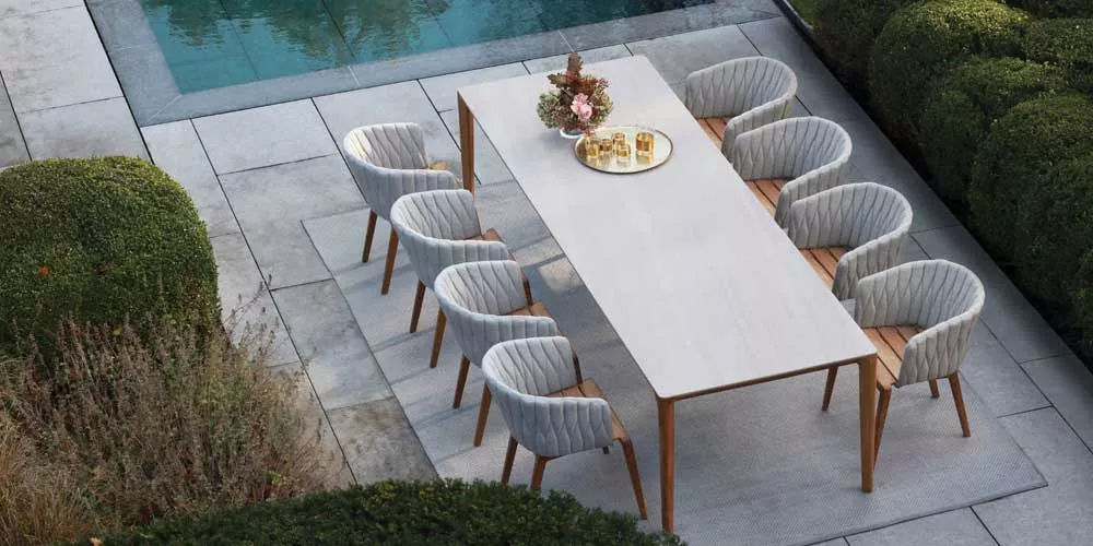 Royal Botania Calypso Essgruppe in Grau auf einer Terrasse neben einem Pool, umgeben von grünen Hecken, aus der Vogelperspektive.