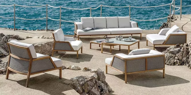 Ethimo Grand Life Outdoor Loungegruppe in Weiß auf einer Terrasse mit Meerblick, bestehend aus Sofa, Sesseln und Couchtisch.