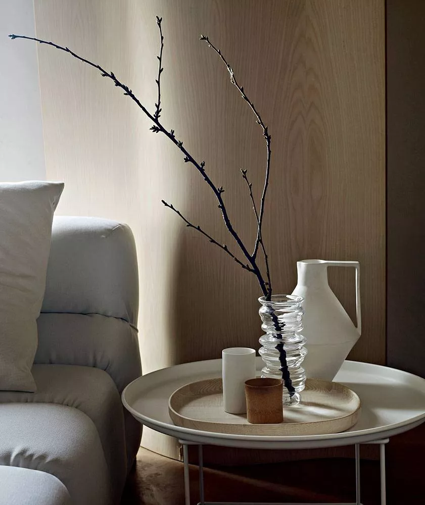 B&B Italia Fat-Fat Beistelltisch mit Vase Zweigen und Kerzen auf einem Tablett neben einem Sofa in einem gemütlichen Wohnzimmer.