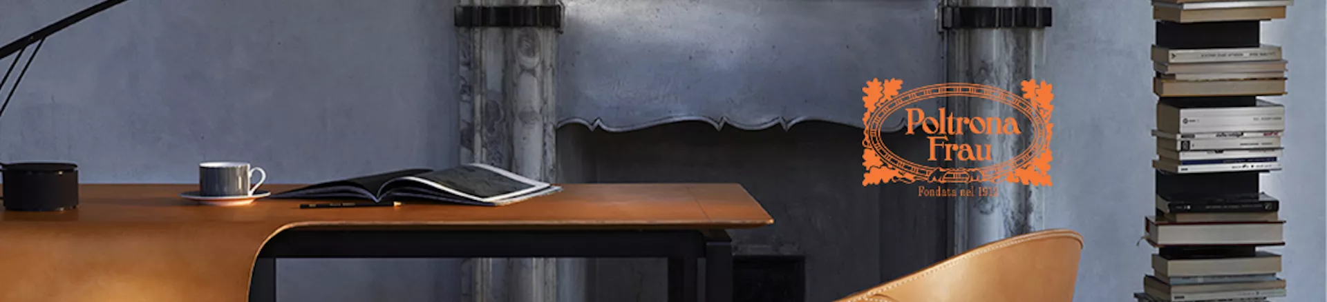 Poltrona Frau Ledersessel in Cognacbraun vor einem Kamin, mit einem Stapel Bücher und einer Tasse auf einem Tisch, stimmungsvolle Wohnzimmerkulisse.