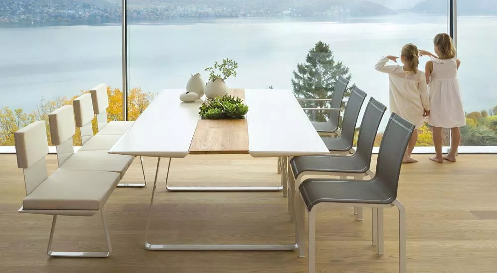 EGO Paris Extrados Essgruppe in Weiß und Grau vor Panoramafenster mit Seeblick, moderne Atmosphäre, Holzboden.