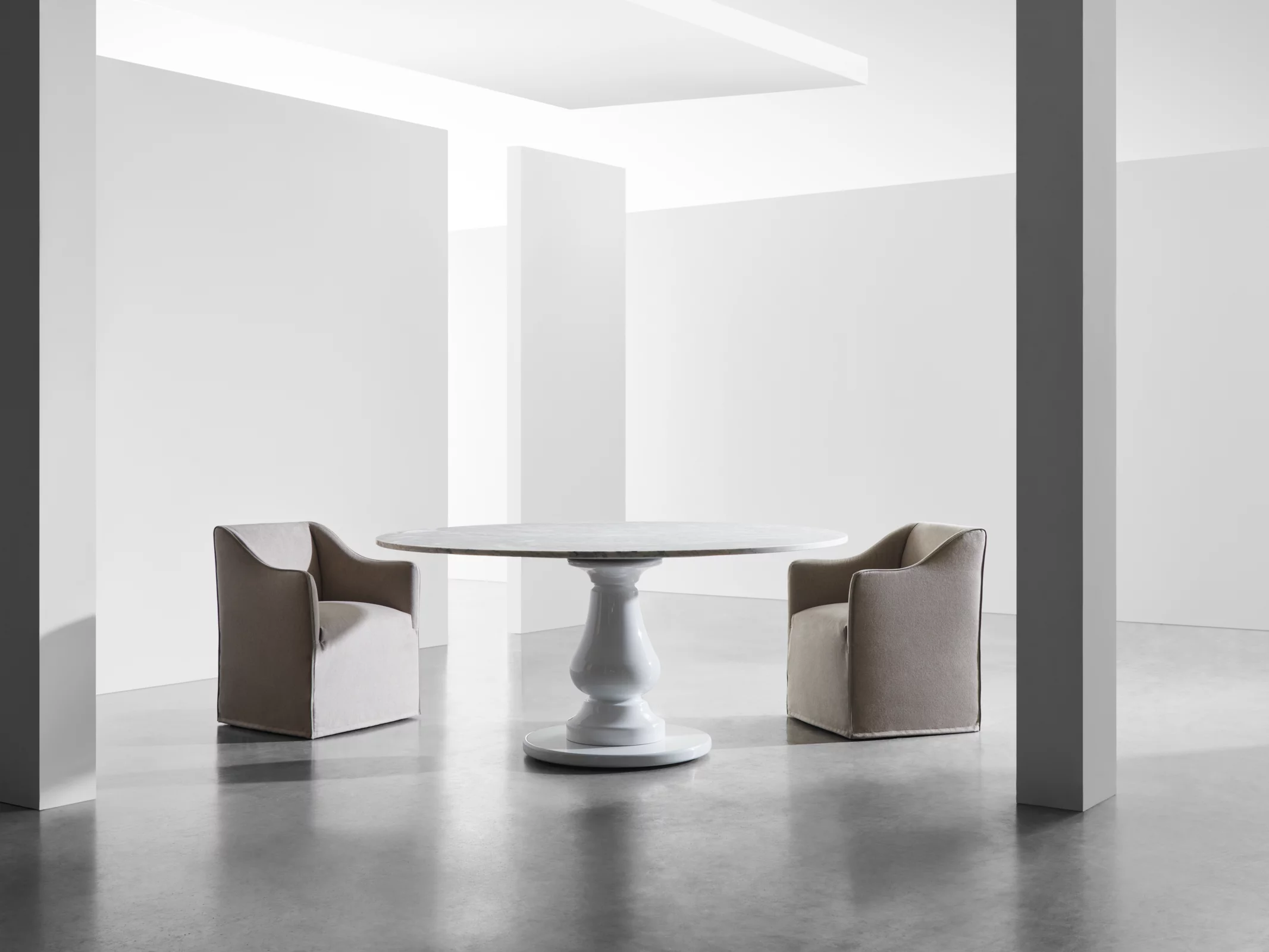 Zwei beige Gervasoni Sessel und ein weißer runder Tisch in einem minimalistischen Raum ohne Hintergrund.