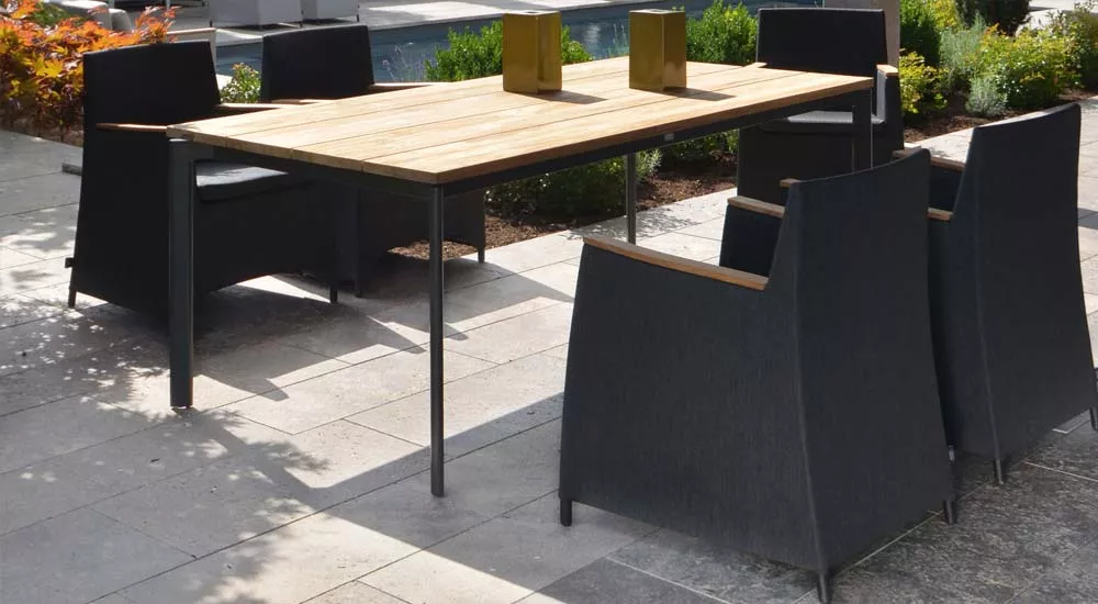 Fischer Möbel Rio Essgruppe in Anthrazit mit Holztisch und sechs Stühlen auf einer Terrasse vor einem Pool, stimmungsvolle Gartenatmosphäre.