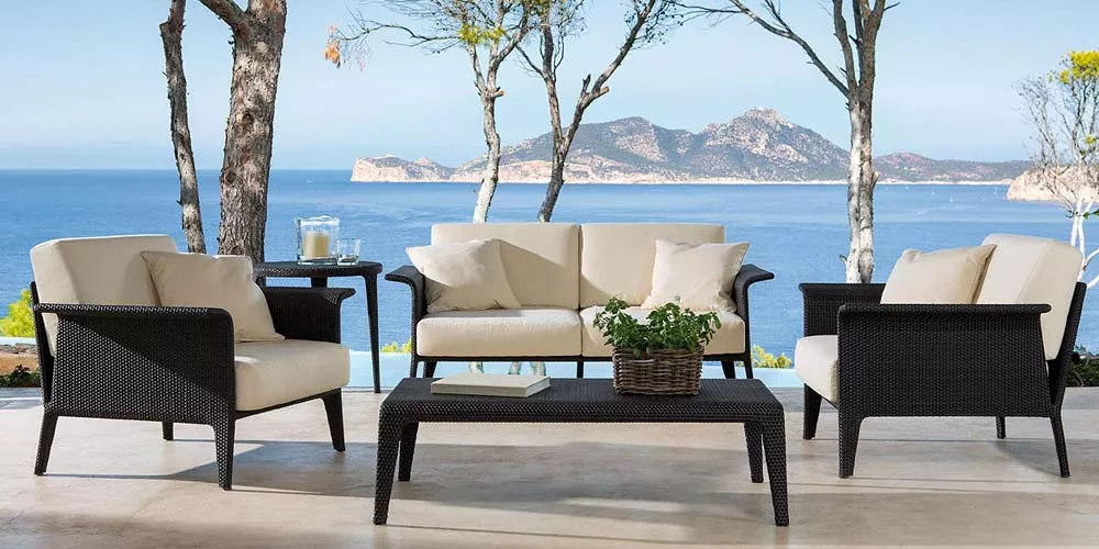 Point U Outdoor-Loungegruppe in Schwarz und Creme auf Terrasse mit Meerblick und Bäumen im Hintergrund.