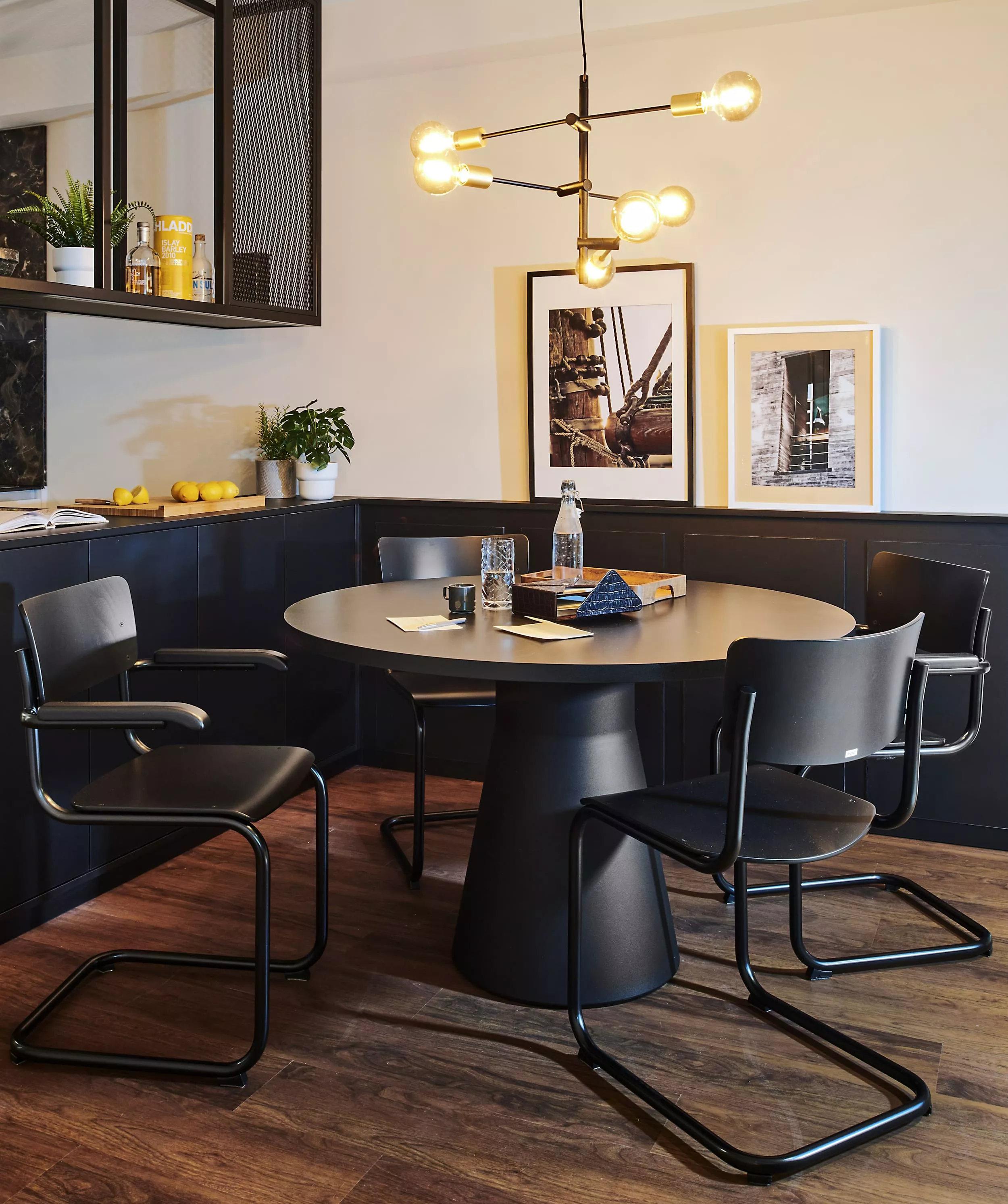 Esszimmer mit Thonet S43F Stühlen um einen runden Tisch mit modernen Leuchten an der Decke und Kunstwerken an der Wand mood picture