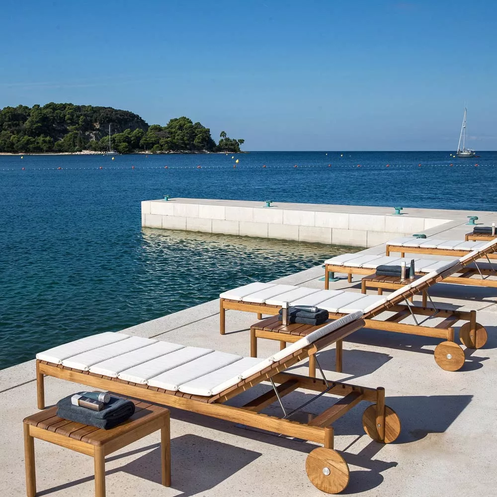 Varaschin Barcode Sonnenliege, 209 cm, Teakholzgestell, rollbar, auf einer Terrasse mit Meerblick und klarem Himmel.