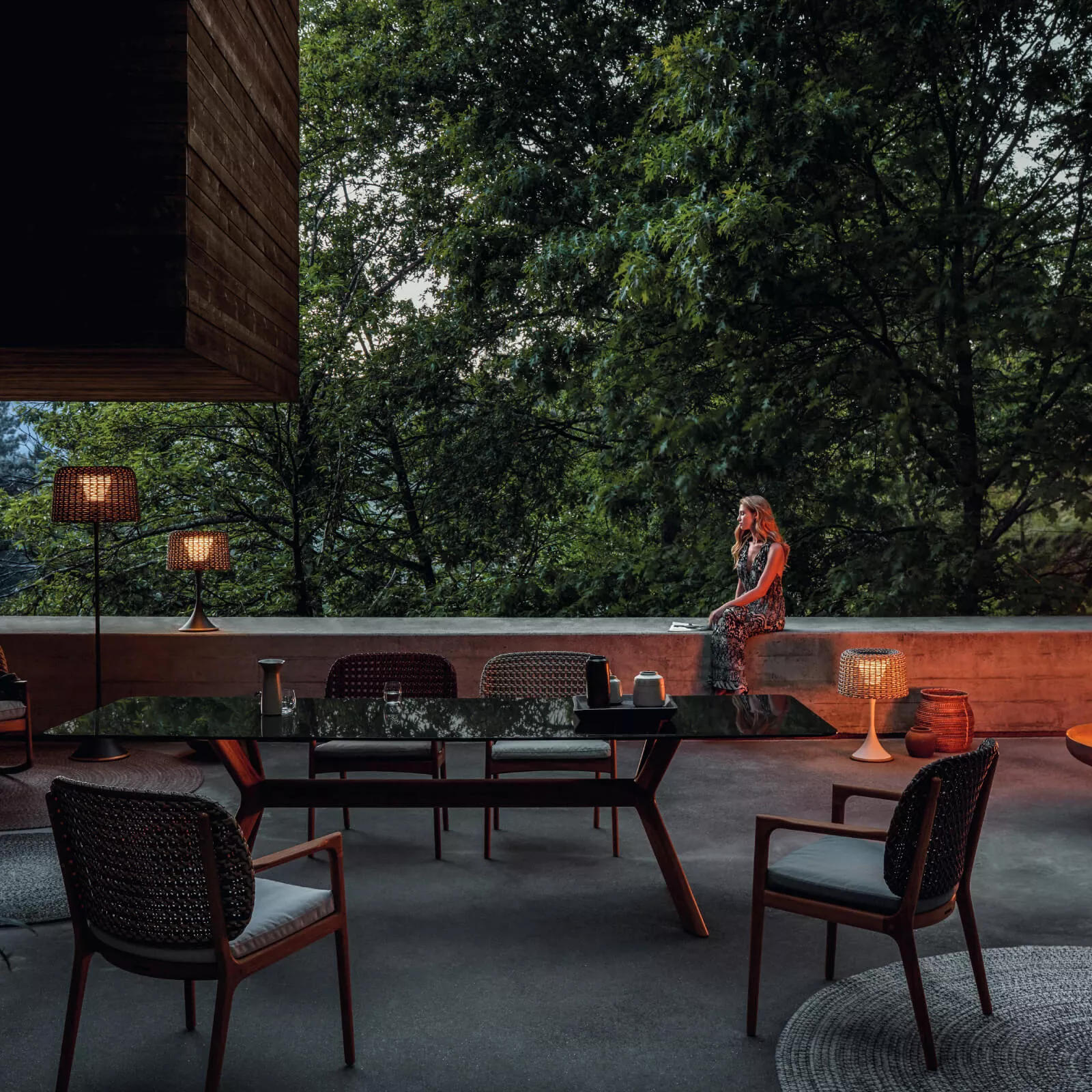 Gloster Feuerschale in einem stimmungsvollen Gartenambiente bei Dämmerung, umgeben von modernen Gartenmöbeln und sanfter Beleuchtung.